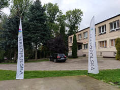 Na zdjęciu budynek szkoły, maszty z logo Małopolska